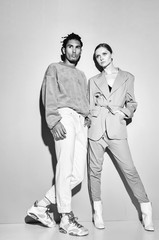 Black and white shot of Casual couple in red leaning against a grey wall