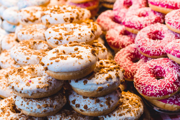 Sweet donuts decorated with colored glaze and powder are sold at the fair and in the shop, pink, white, chocolate