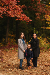 Portrait of happy family in autumn park. Mothe with two daughter. Two sister with mom