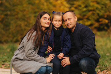 Father and two daughters in the forest. Autumn weather and colorful background. Happy family. Two sister show their love to dad