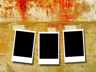 Three blank rectangular instant photo frames on dirty weathered concrete wall background