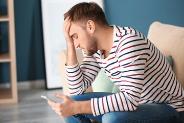 Lonely depressed man with mobile phone at home
