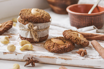 Homemade nutty vegan cinnamon cookies on white beige wooden board, close-up, natural light
