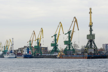 Obraz premium Sea port with cranes, ships at the pier for loading goods.