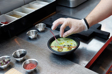 Chef is adding herbs to a dish, professional kitchen