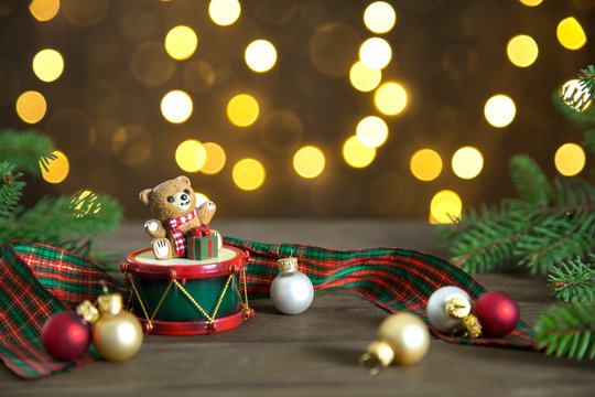 Christmas composition with cute teddy bear, glass balls and fir, on a wooden top with bokeh of lights