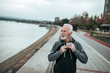 Active sporty senior man walking by the river. - obrazy, fototapety, plakaty