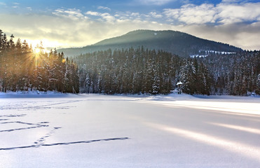 Ice covered and snowy Synevyr lake in winter, gorgeous location in forested Carpathian mountains