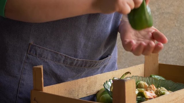 Female cook in an apron with is preparing a sweet pepper stuffed with meat in kitchen. Girl fills peppers with minced meat and puts in pan for cooking.