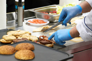 The chef prepares many hamburgers on the table in the restaurant.