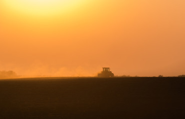 Plowing of stubble field at sunset