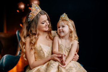 portrait of young mother and little daughter in luxurious dresses