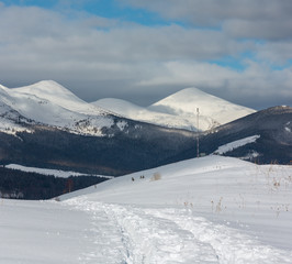 Sledge trace and footprints on winter mountain hill top