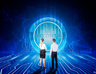 Back view of young businessman and woman looking at information technology processes and big data...