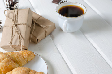 Cup of hot coffee with pastry, new year packs and pine cones