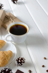Cup of hot coffee with pastry, new year packs and pine cones