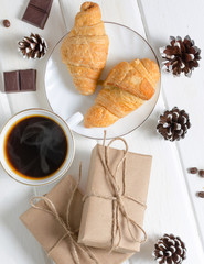 Cup of hot coffee with pastry, new year packs and pine cones