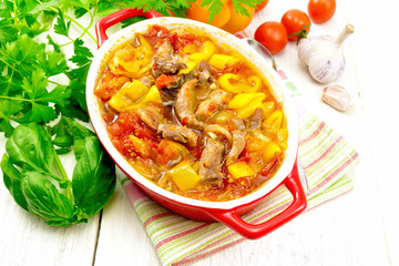 Ragout of meat and vegetables in red brazier on light board