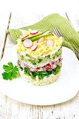 Salad layered with radish and cucumber on light board
