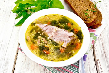 Soup with couscous and spinach in plate on light board