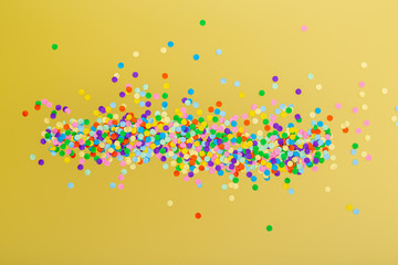 Colorful confetti on yellow background.