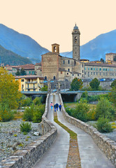 detail of the old Roman bridge with stone arch and river flowing in the middle of the rocks in the medieval village Bobbio on the hills near Piacenza, Italy - obrazy, fototapety, plakaty