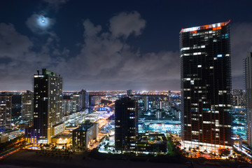 Fototapeta na wymiar Moon over city with highrise buildings drone photography