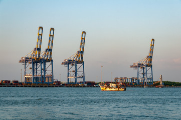 Fishing boat puts out to sea from Cochi port, with heavy industry in the background