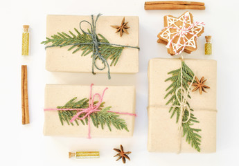 Cozy holiday white background. Christmas composition of spruce branches, gift, gingerbread cookies, cinnamon, anise and confetti in small jars. Flat lay, top view