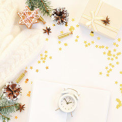 Cozy holiday white background in Scandinavian style. Christmas composition of gifts, knitted mittens, ginger cookies, anise and confetti in small jars. Notebook and watch for an appointment.