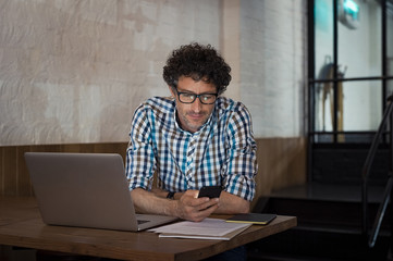 Man using laptop and smartphone at cafe