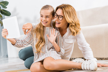 selective focus of happy grandmother and granddaughter waving by hand and having video call with digital tablet at home