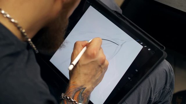 Guy draw picture on tablet computer. Designer works on graphic tablet at PC 