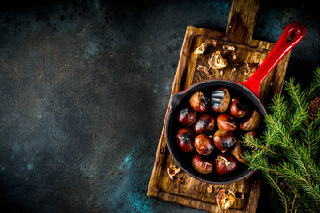 Cracked roasted chestnuts, traditional autumn winter homemade snack, on small chestnut's frying pan, copy space