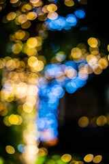 Fototapeta premium Beautiful bokeh of colorful Christmas lights in a city (Blurry background of illumination and decoration of trees in holiday night)
