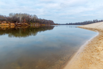 The autumnal landscape with the calm river, the sandy beach and leafless forest on the other side. Stogovskaya Spit, Don river, Rostov-on-Don region, Russia