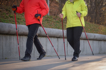 Nordic walking. A man and a woman are doing sports in the park.