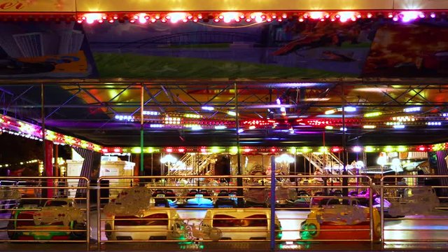 Fascinating steady time lapse view on children kart racing attraction in colorful neon flashing lights in amusement park