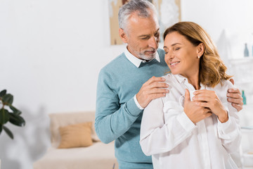 Fototapeta premium handsome mature man embracing beautiful wife with coffee cup at home