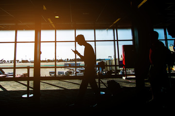 Naklejka na ściany i meble Silhouette of people walk at airport for traveling. subject is blurred and low key.