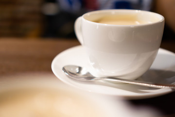 White porcelain cup of milk tea (tea with milk isolated) with teaspoon on a table (a cafe in Jimbocho, Tokyo)