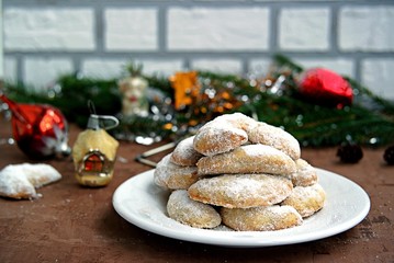 Shortbread with walnuts, covered with powdered sugar, on a white plate in the New Year and Christmas style. Merry christmas and happy new year concept.