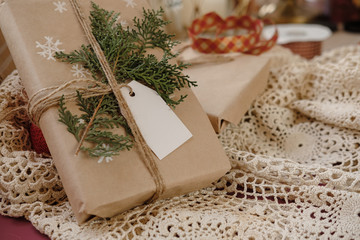 Blank Gift tag on Classy vintage Christmas gift box on lace tablecloth background. Christmas presents with handmade decoration. Close up. Mockup. Copy space.