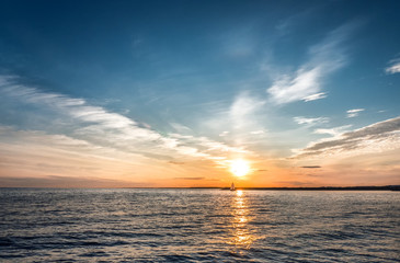 Fototapeta premium Ship out at sea at sunset. A sunny trail on the water and amazing clouds.