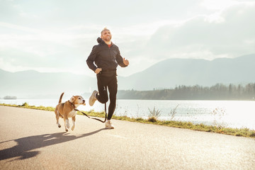 Fototapety  Poranny jogging ze zwierzakiem: mężczyzna biega razem ze swoim psem rasy beagle