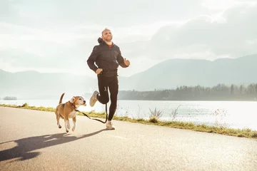 Fotobehang Joggen Ochtend joggen met huisdier: man rent samen met zijn beagle hond