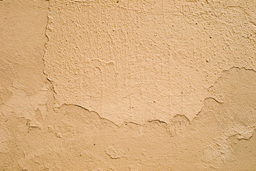 Wall with cracks in the yellow plaster