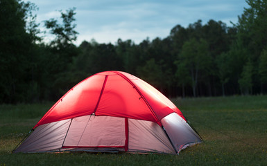 Nylon tent lighted in a field after sunset