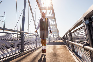 Sports man jumping with skipping rope at bridge