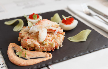 Russian salad with crab meat on slate plate